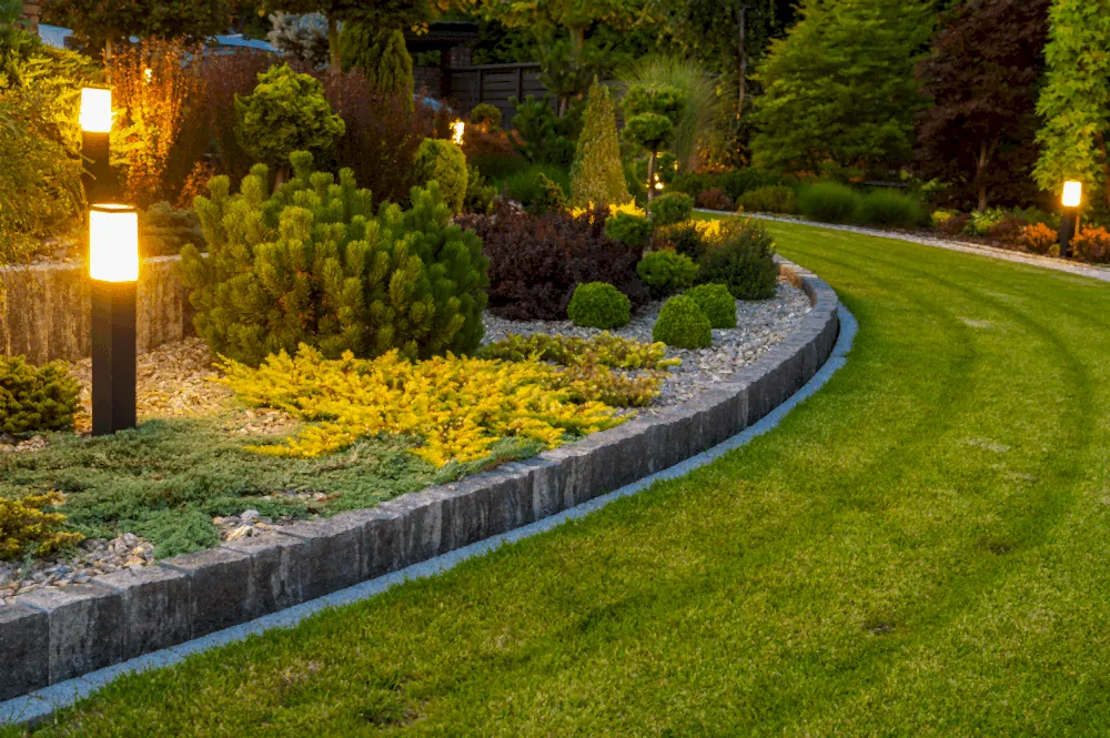 A well-maintained landscape design featuring a stone wall illuminated by decorative lights, designed in Eagle, Idaho.